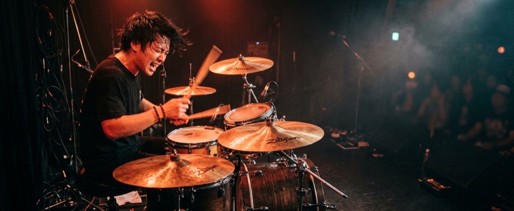ライブハウスのステージでドラムを叩くドラマー